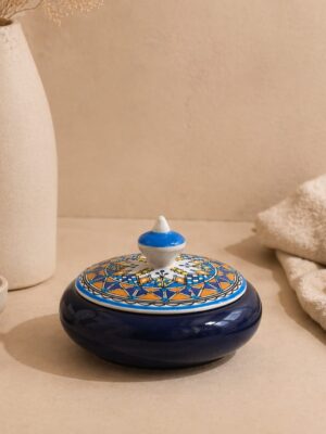 Boîte à bijoux artisanale en céramique bleue avec couvercle décoré de motifs traditionnels, présentée sur un fond beige.